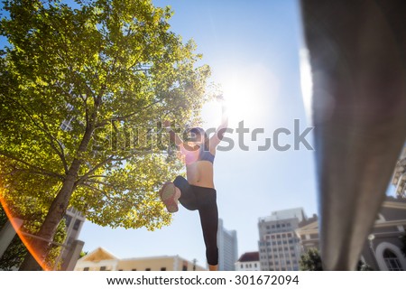 Athletic woman leaping and holding arms up in the air in the city