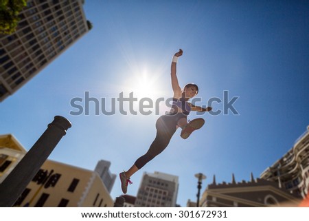 Athletic woman jumping off the bollard in the city