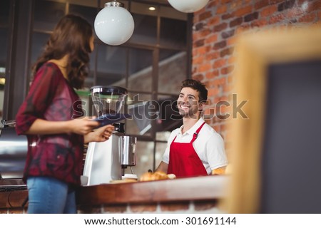 Handsome barista discussing with a customer at the coffee shop