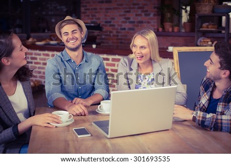 Smiling friends drinking coffee and laughing at coffee shop