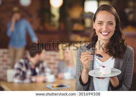 Portrait of smiling young woman holding cake in front of her friends at coffee shop