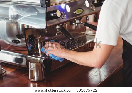 Barista cleaning coffee machine at coffee shop