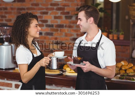Waiter and waitress smiling at each other at coffee shop