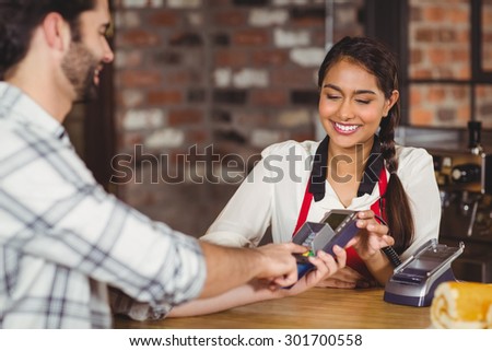 Smiling customer typing on the pin terminal at the coffee shop