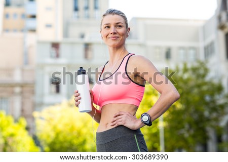 A beautiful woman holding a sports bottle of water on a sunny day