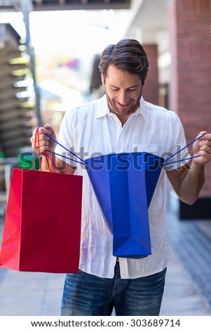A happy smiling man looking into his shopping bags in a clothing store