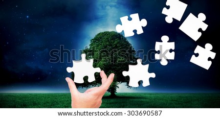 Businessman pointing with his finger against tree in field at night