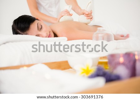 Pretty woman enjoying a herbal compress massage at the health spa