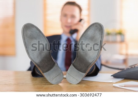 Relaxed businessman making a phone call in his office
