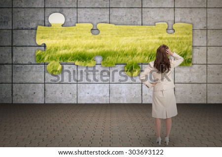 Businesswoman standing back to camera with hand on head against green meadow