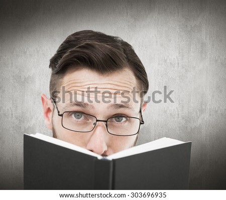 Young geek looking over black book against white and grey background
