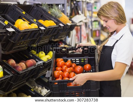 Smiling staff woman holding a box with fresh vegetables at supermarket