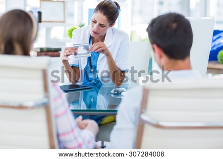 Doctor showing sonagram to couple in office at the hospital
