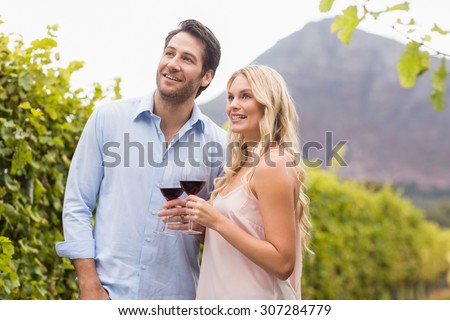 Young happy couple smiling and looking in the distance in the grape fields