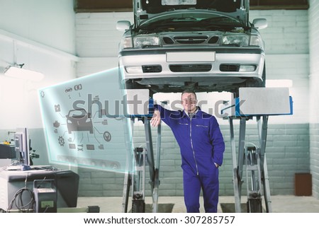 Engineering interface against smiling mechanic leaning on a machine below a car