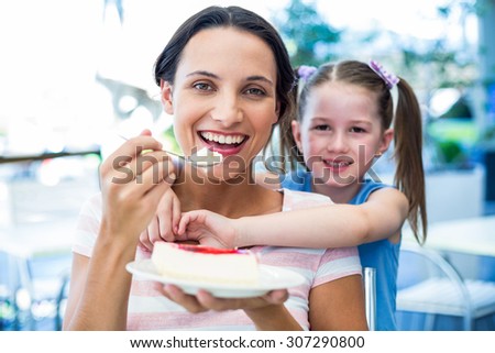 Mother eating a piece of cake with her daughter at the cafe