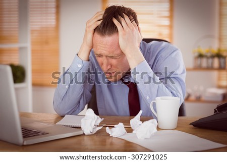Stressed businessman with head in hands at office
