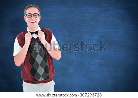 Geeky hipster fixing his bow tie against blue chalkboard