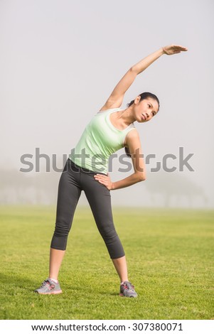 Sporty woman stretching arms in parkland