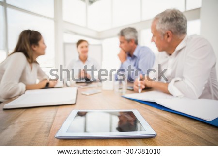 Tablet in front of talking business people in the office
