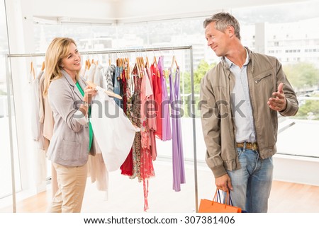 Smiling woman showing clothes to her man in clothing store
