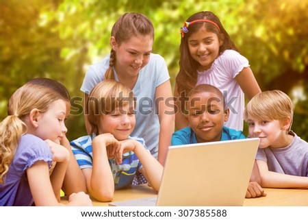 Cute pupils using tablet computer in library against trees and meadow in the park