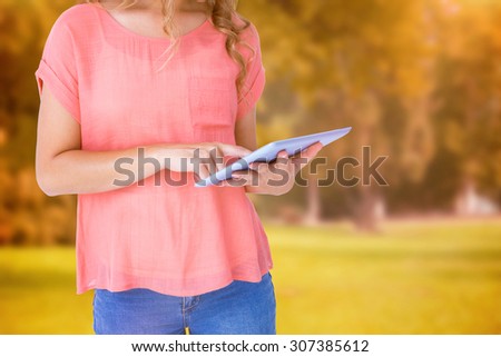 Hipster woman holding tablet pc against trees and meadow