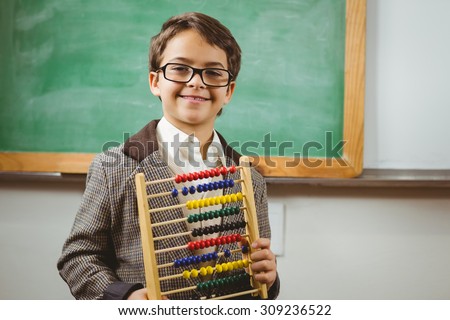 Portrait of smiling pupil dressed up as teacher holding abacus in a classroom