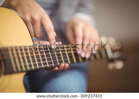 Teacher giving guitar lessons to pupil in a classroom