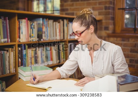 Blonde teacher correcting in the library in school