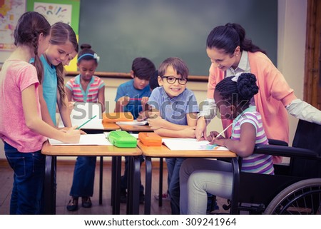 Pupils and teacher working at desk together at the elementary school