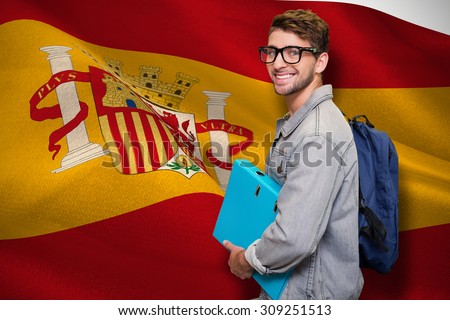 Student smiling at camera in library against digitally generated spanish national flag
