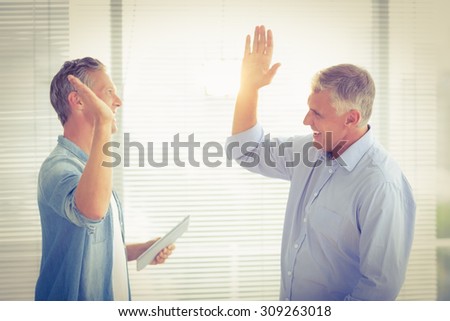 Smiling business colleagues giving high-five at the office