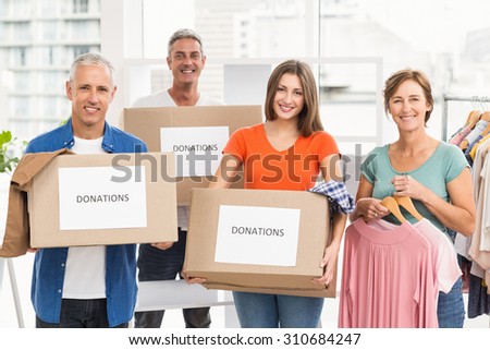 Portrait of smiling casual business people with donation boxes in the office