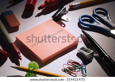 The word vocational education against students table with school supplies