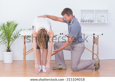 Doctor stretching a woman back in medical office