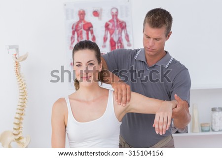 Doctor stretching a young woman arm in medical office