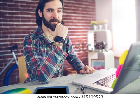 Portrait of confident businessman with graphic tablet and laptop in creative office