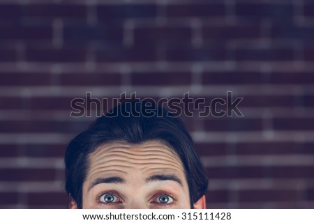 Portrait of man with raised eyebrows against brick wall
