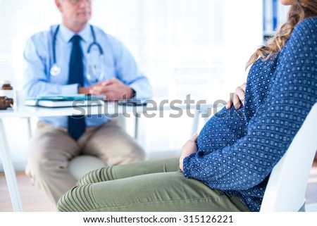 Pregnant woman consulting male doctor white sitting in clinic