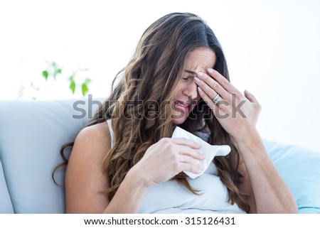 Sick woman crying on sofa at home