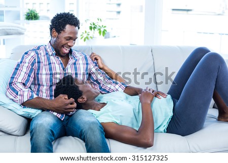 Pregnant wife relaxing on husband lap at home