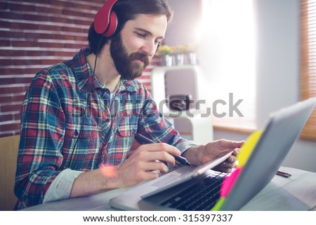 Smart businessman wearing headphones while using graphic table at office