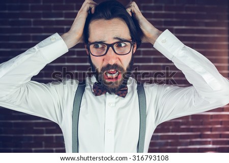 Worried man with head in hands looking away against brick wall