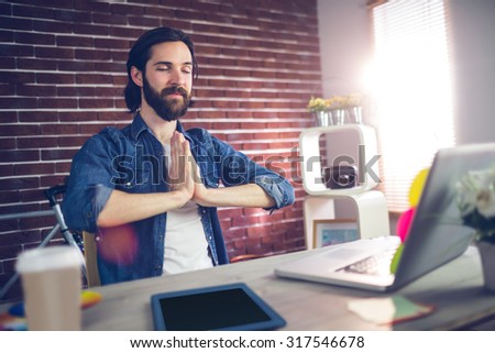 Businessman with hand clasped doing yoga in creative office