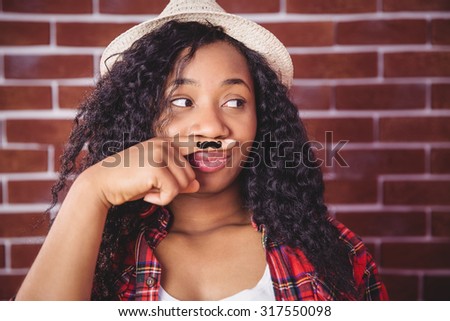 Hipster with mustache on finger on red brick background
