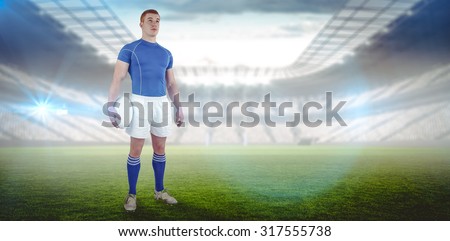 Rugby player holding a rugby ball against rugby stadium