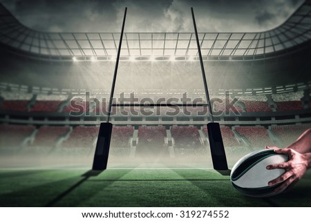 Close-up of of sports player holding ball against rugby pitch