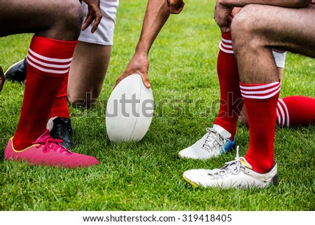 Rugby players in huddle with ball at the park