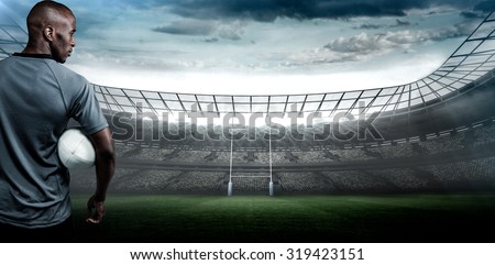 Rear view of sportsman with rugby ball against rugby stadium